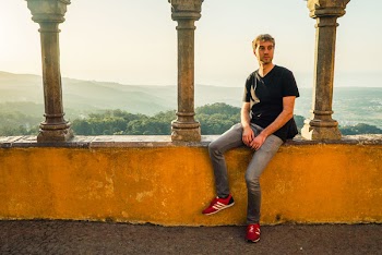 Man Sitting on Concrete Terrace With Mountain Overview