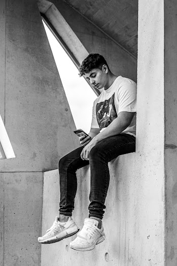 Man Sitting on Concrete Wall