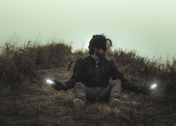 man sitting on dried grass field during daytime