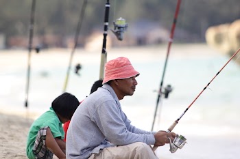 Man Sitting on Edge Fishing on River