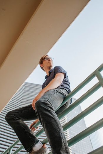 man sitting on gray rail