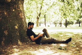 Man Sitting on Ground Against Tree