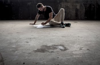 man sitting on ground while writing on paper