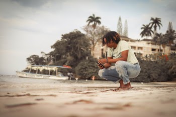 Man Sitting on His Feet Near Body of Water