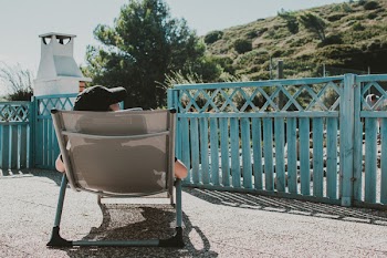 Man Sitting on Lounger Near Blue Wooden Fence
