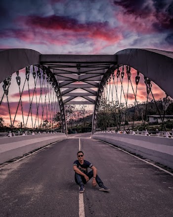 Man Sitting on Middle of Bridge