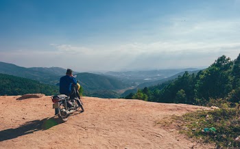 Man Sitting On Motorcycle Facing Mountains