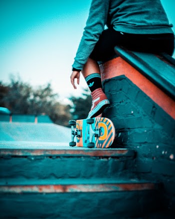 Man Sitting on Railing While Foot on Skateboard