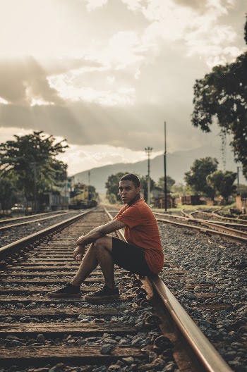 Man Sitting on Railroad during Day