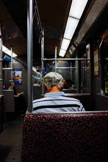 Man Sitting on Red and Black Floral Padded Seat Inside Train