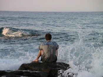 Man Sitting on Rock and Water Splashing