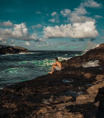 Man Sitting on Rock Beside Sea
