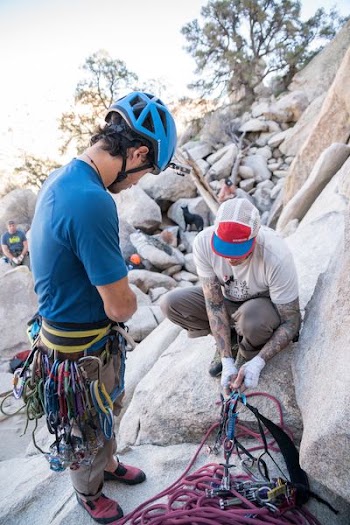 man sitting on rock fixing safety harness