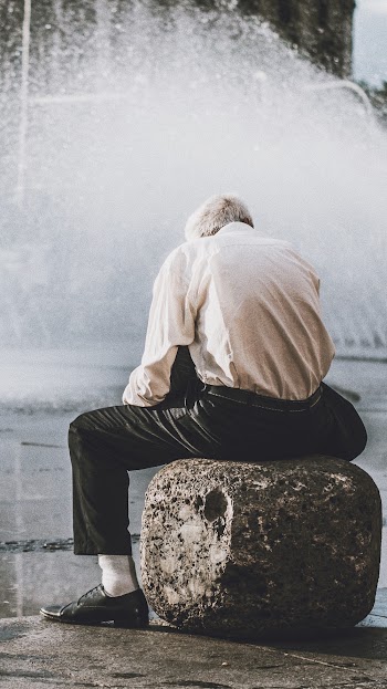 Man Sitting on Rock in Front of Water Fountain