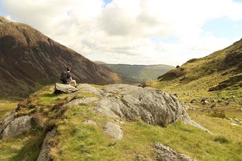 man sitting on rock near mountain during daytime