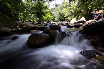 Man Sitting on Rock Near the Waterfalls