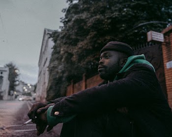 Man Sitting on Side Street  Holding Cigarette
