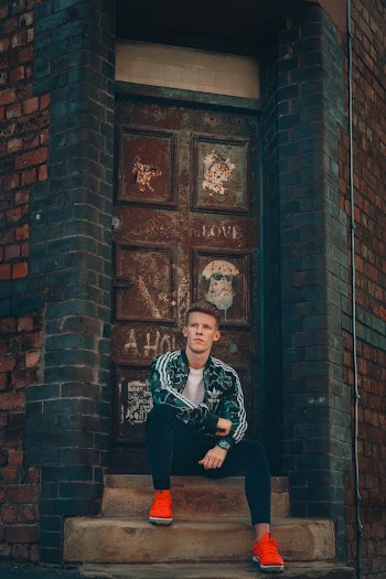 Man Sitting on Stairs Outside a Rusty Metal Door
