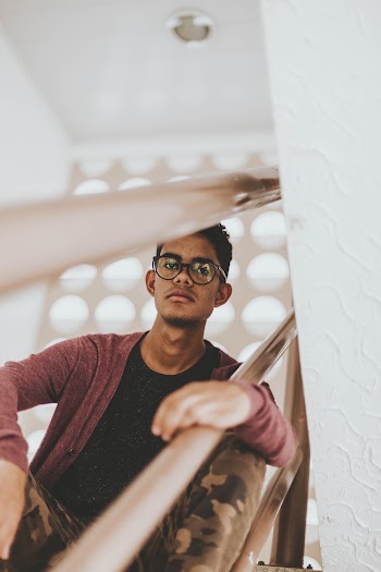 Man Sitting on Stairs While Holding on Railings