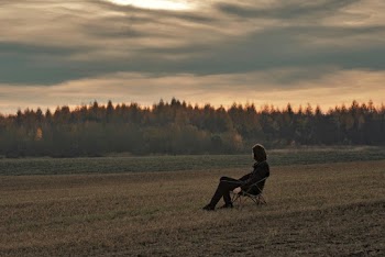 Man Sitting on the Chair on the Grass Field