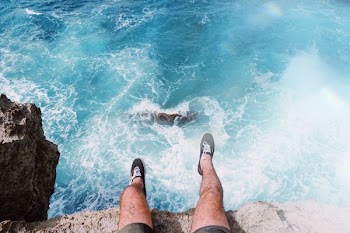 man sitting on the edge of a cliff