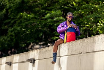 Man Sitting on Top of a White Concrete Wall