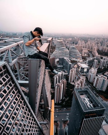 man sitting on top of building taking photo below