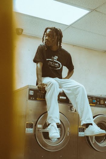 man sitting on top of front-load clothes washer