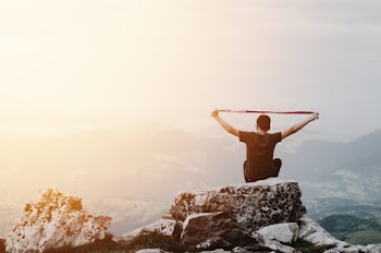 Man Sitting on Top of Rock