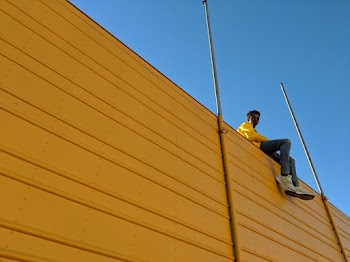 Man Sitting on Top of Yellow Building