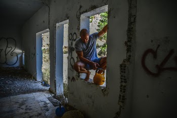 Man Sitting on Window Beside Yellow Kettlebell