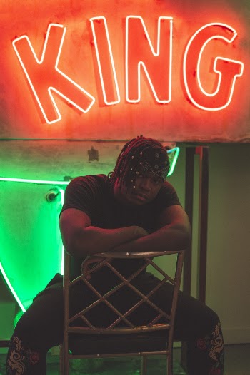 Man Sitting Under An Illuminated Sign Board