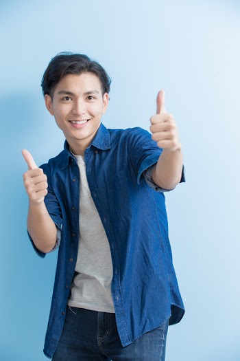 man smile and show thumb up to you isolated on blue background,asian