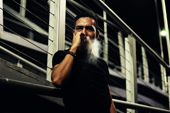 Man Smoking Near Bridge