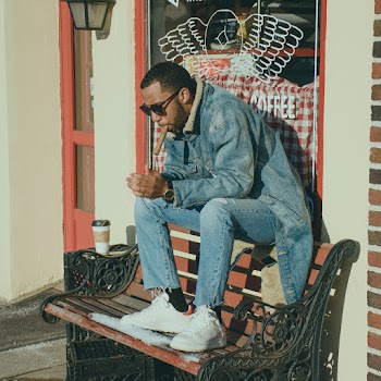Man Smoking Tobacco Sitting on Bench Near Wall