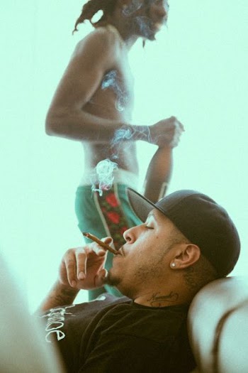 man smoking while lying on brown sofa