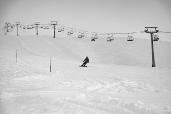 Man Snowboarding Below Cable Carts during Day