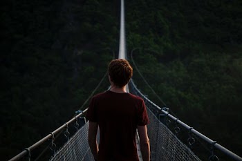 man standing alone on hanging bridge
