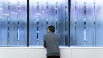 Man Standing and Facing on Glass Wall