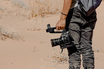 Man Standing and Holding Dslr Camera