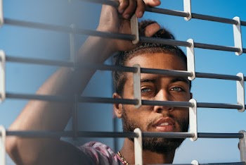 Man Standing Behind Metal Grill