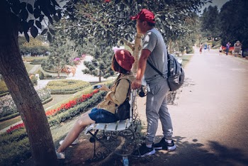 Man Standing Behind Woman Sitting On Bench