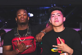 Man Standing Beside Another Man Making Hand Signs
