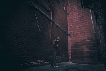 Man Standing Beside Brown Concrete Wall