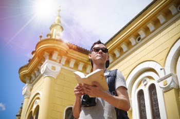 Man Standing Beside Building Holding Open Book