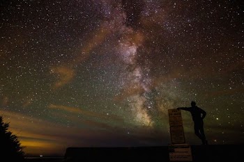 man standing beside monument under polar lights
