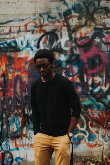 Man Standing Beside Multicolored Painted Concrete Wall