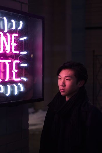 man standing beside pink and blue neon light signage