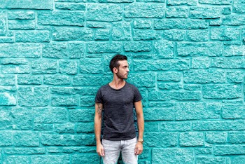 Man Standing Beside Teal Wall