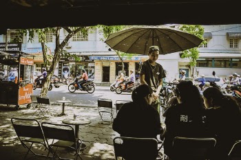 Man Standing Beside Umbrella Facing Three Women Sitting On Chairs